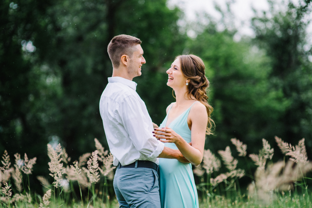 A couple outdoors, embracing and laughing together on a sunny day