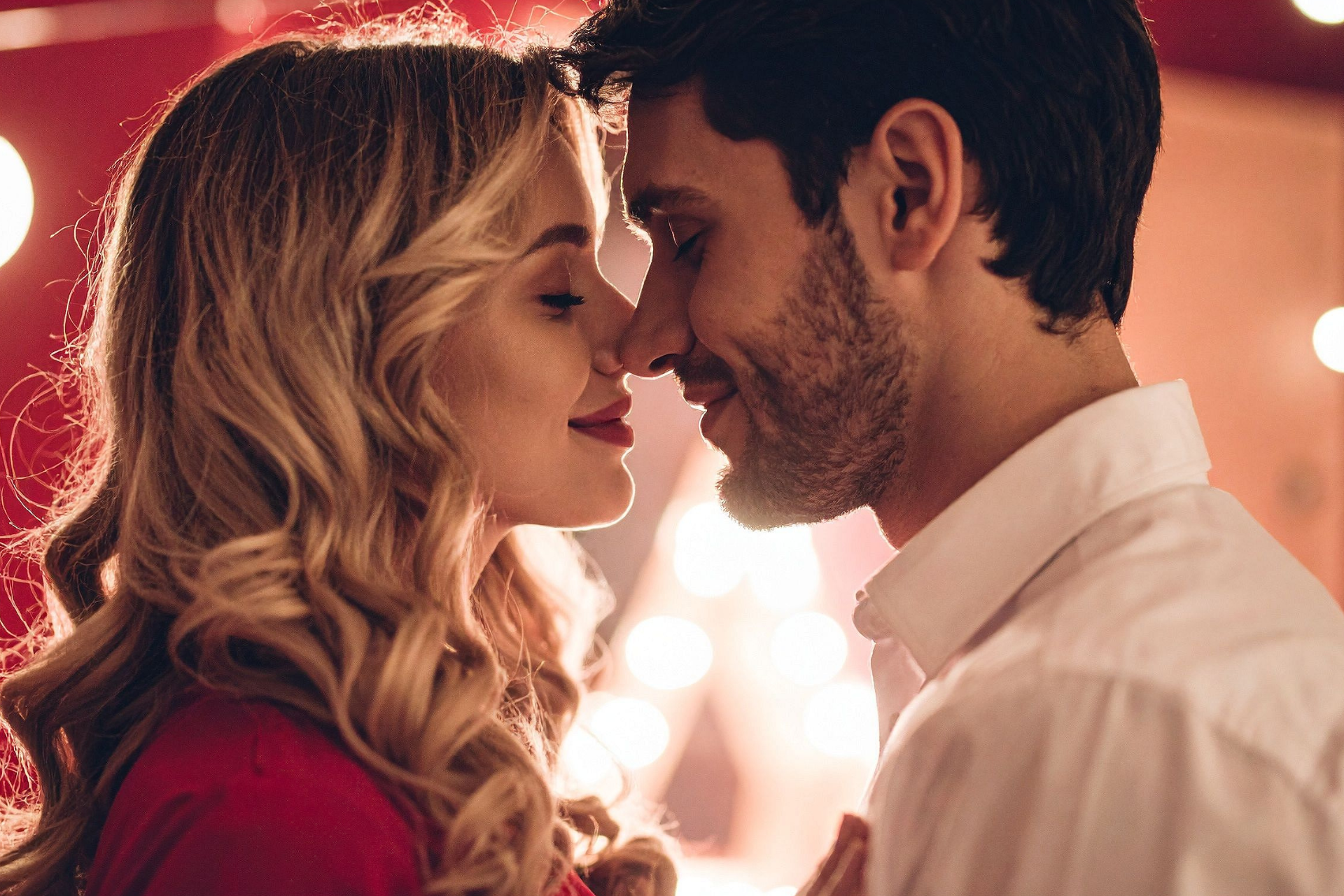 A couple with their eyes closed, smiling softly while touching their noses together
