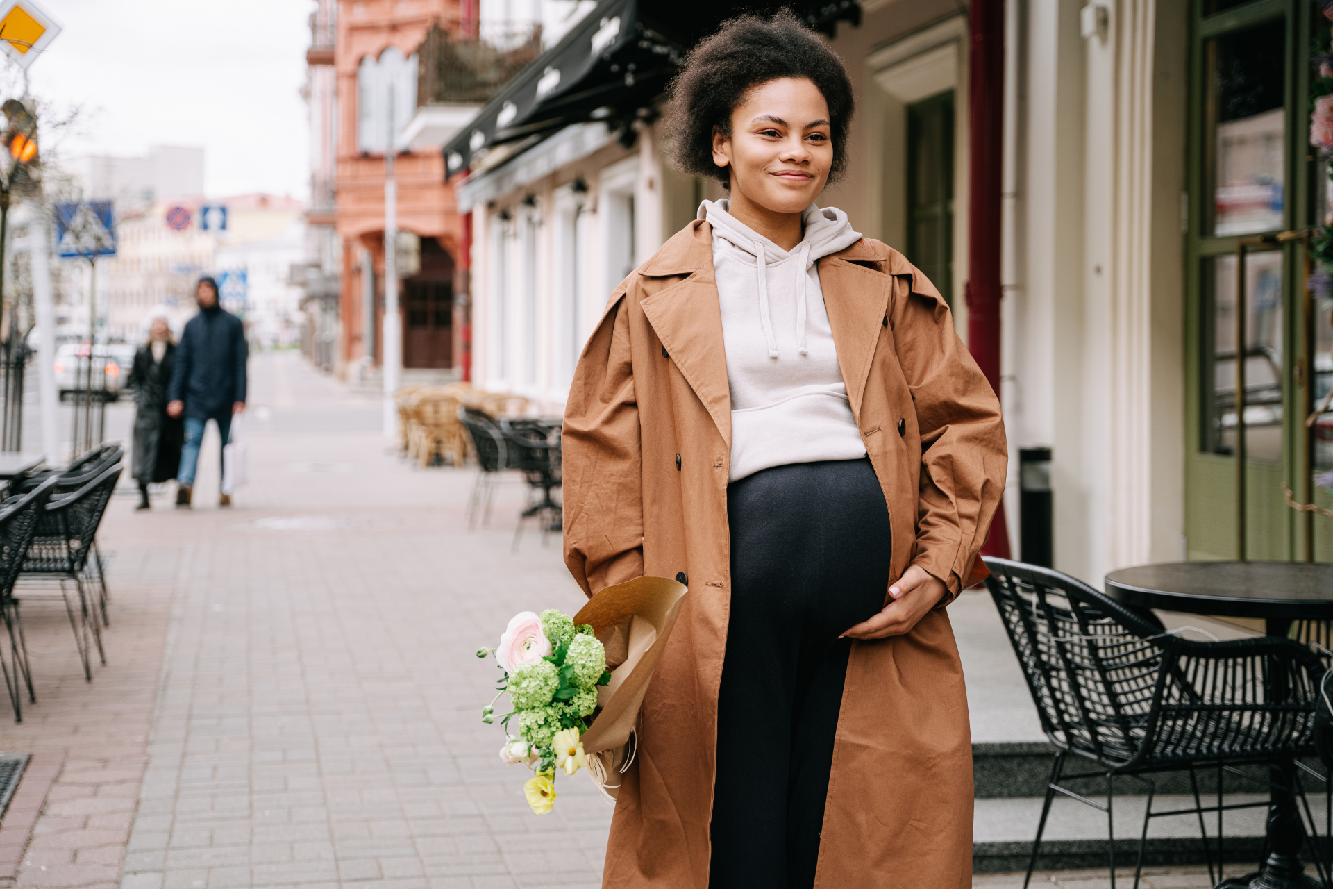 Pregnant Woman Walking Calmly While Holding Her Belly A pregnant woman walking down a street alone, looking calm and happy, with one hand resting on her belly