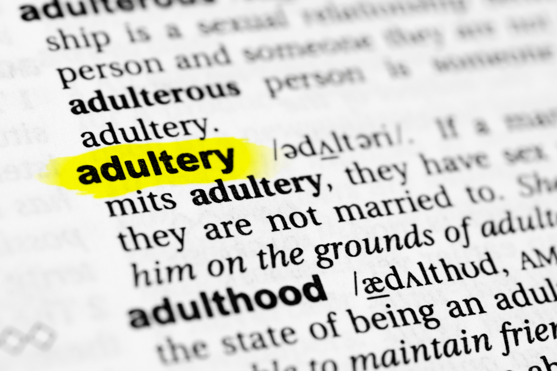 A dictionary page with the word “adultery” highlighted, emphasizing its definition in a printed reference book