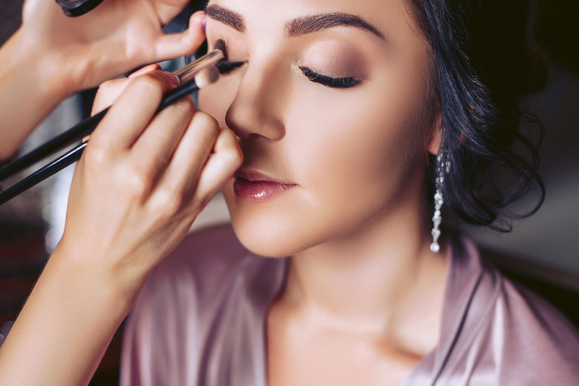 Bride getting eye makeup applied A close-up of a bride as a makeup artist applies eyeshadow, with only the artist’s hands visible during the preparation process