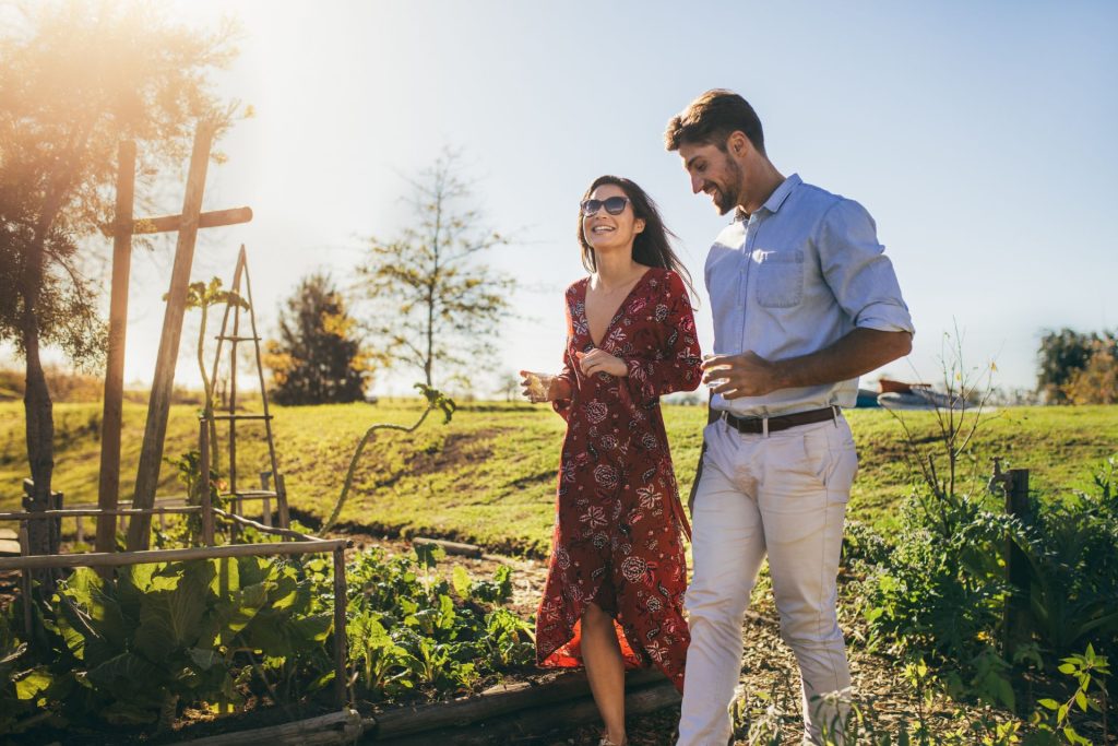 A couple walking together across a grassy meadow on a sunny day, enjoying a peaceful moment outdoors