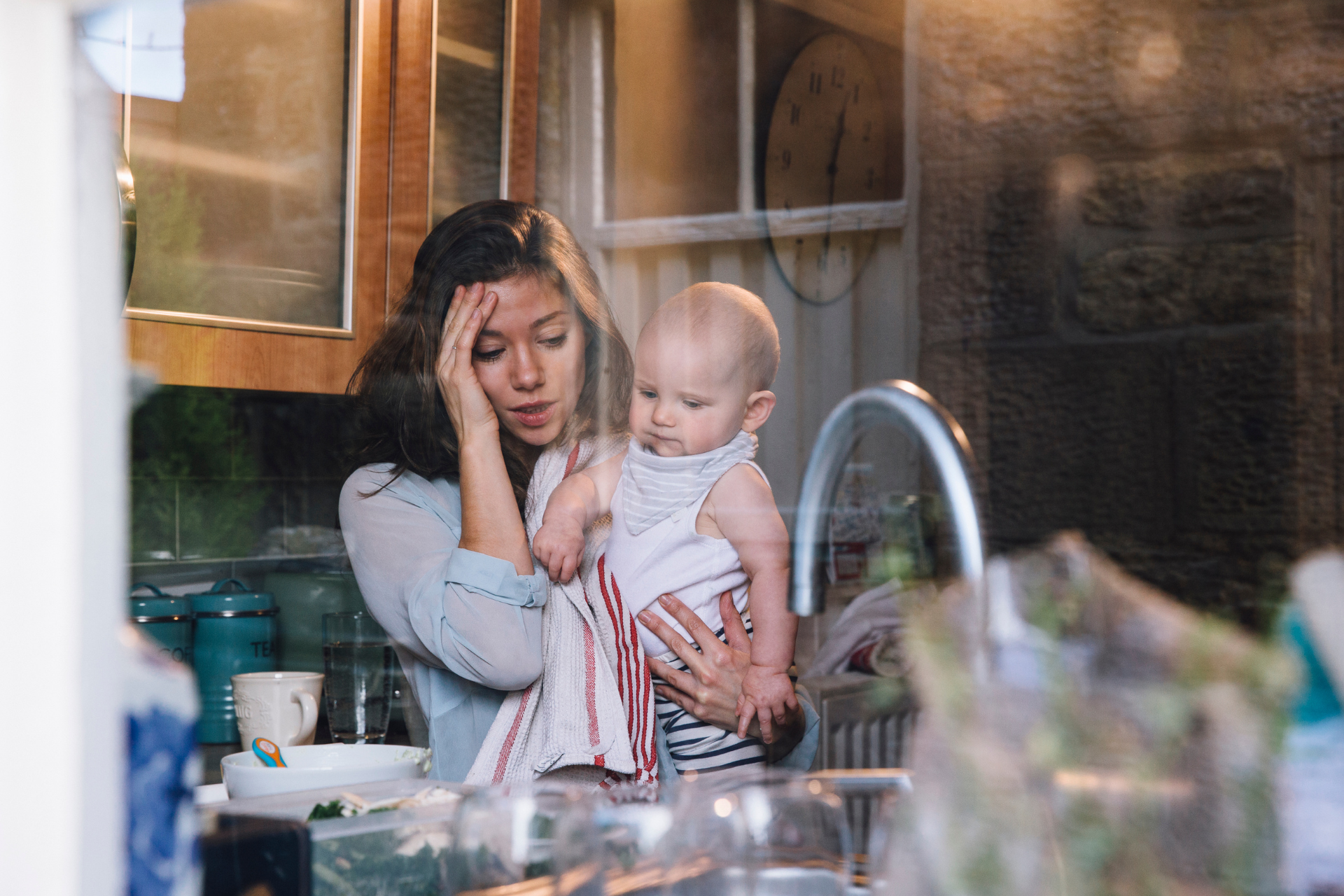 Stressed bride holding baby at home A woman at home holding a baby in her arms, appearing overwhelmed and stressed while managing wedding planning responsibilities