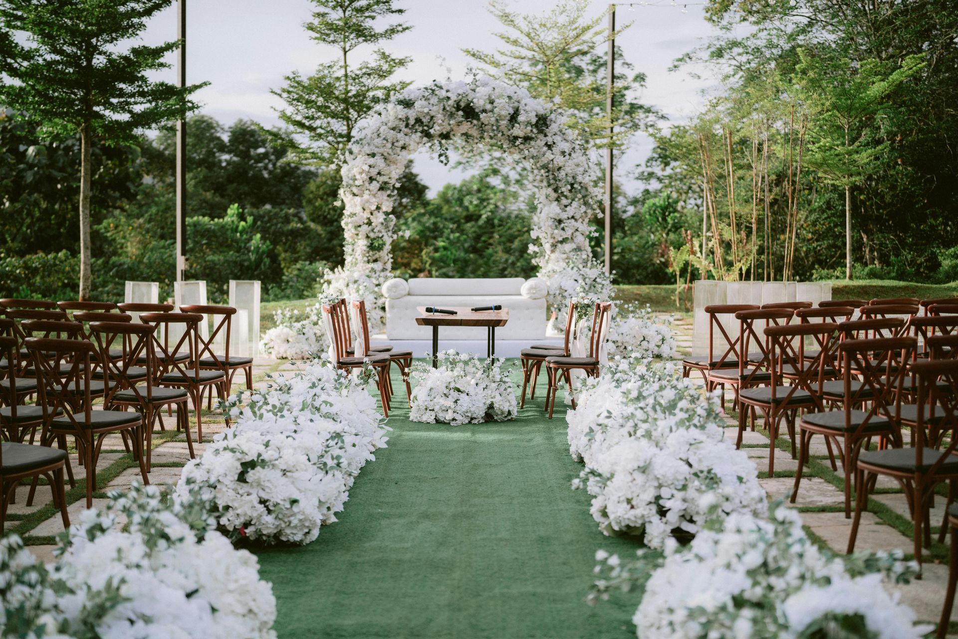 A beautifully decorated wedding altar with elegant white flowers and chairs adorned with floral arrangements, creating a romantic ceremony setting