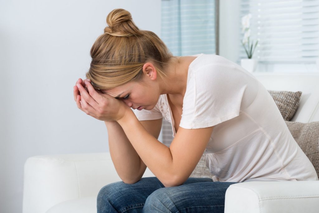 A woman sitting with her hands on her head, expressing stress and frustration through her body language