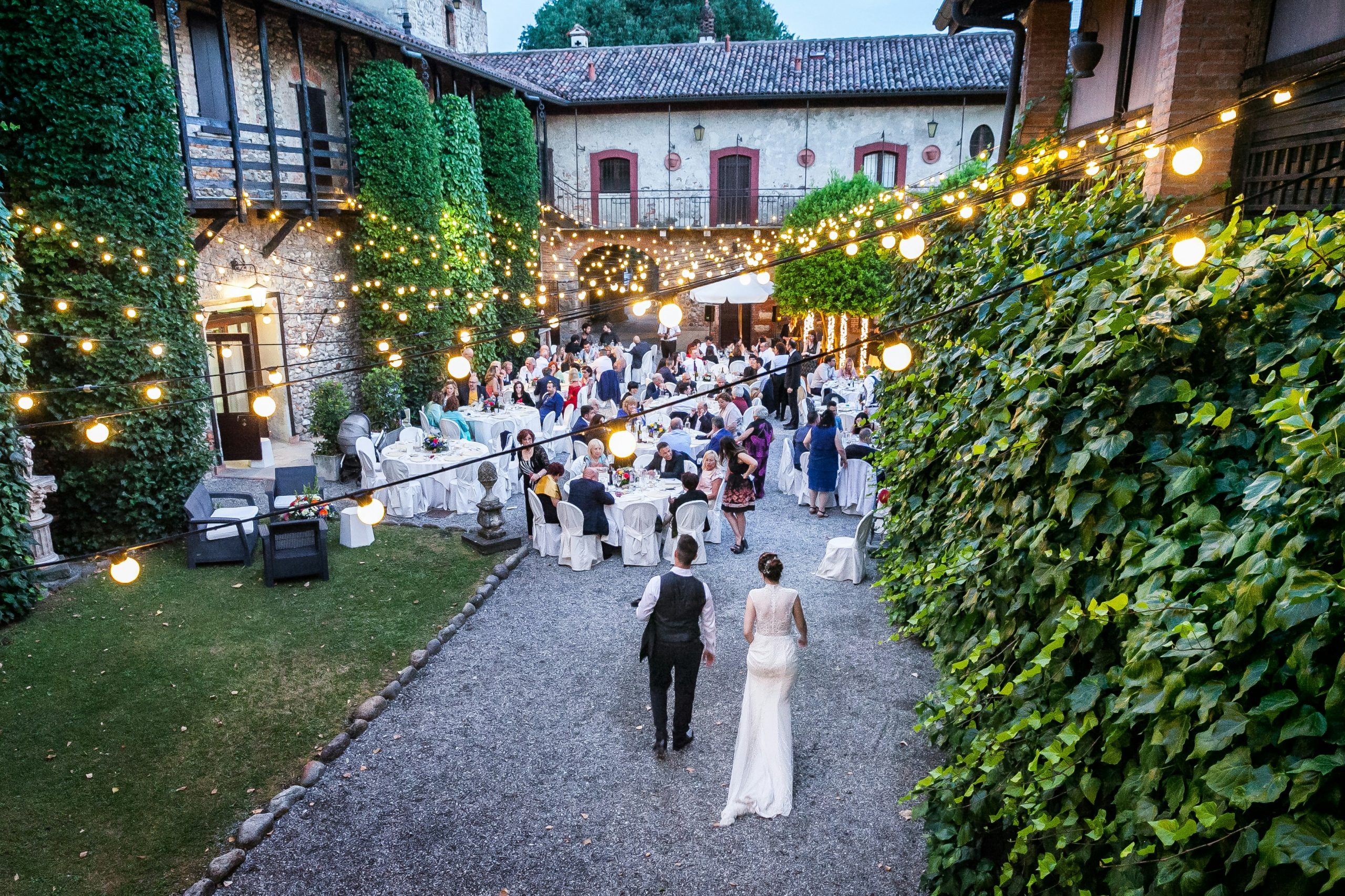 A drone shot capturing a bride and groom walking toward their reception, where friends and family are gathered to celebrate their wedding