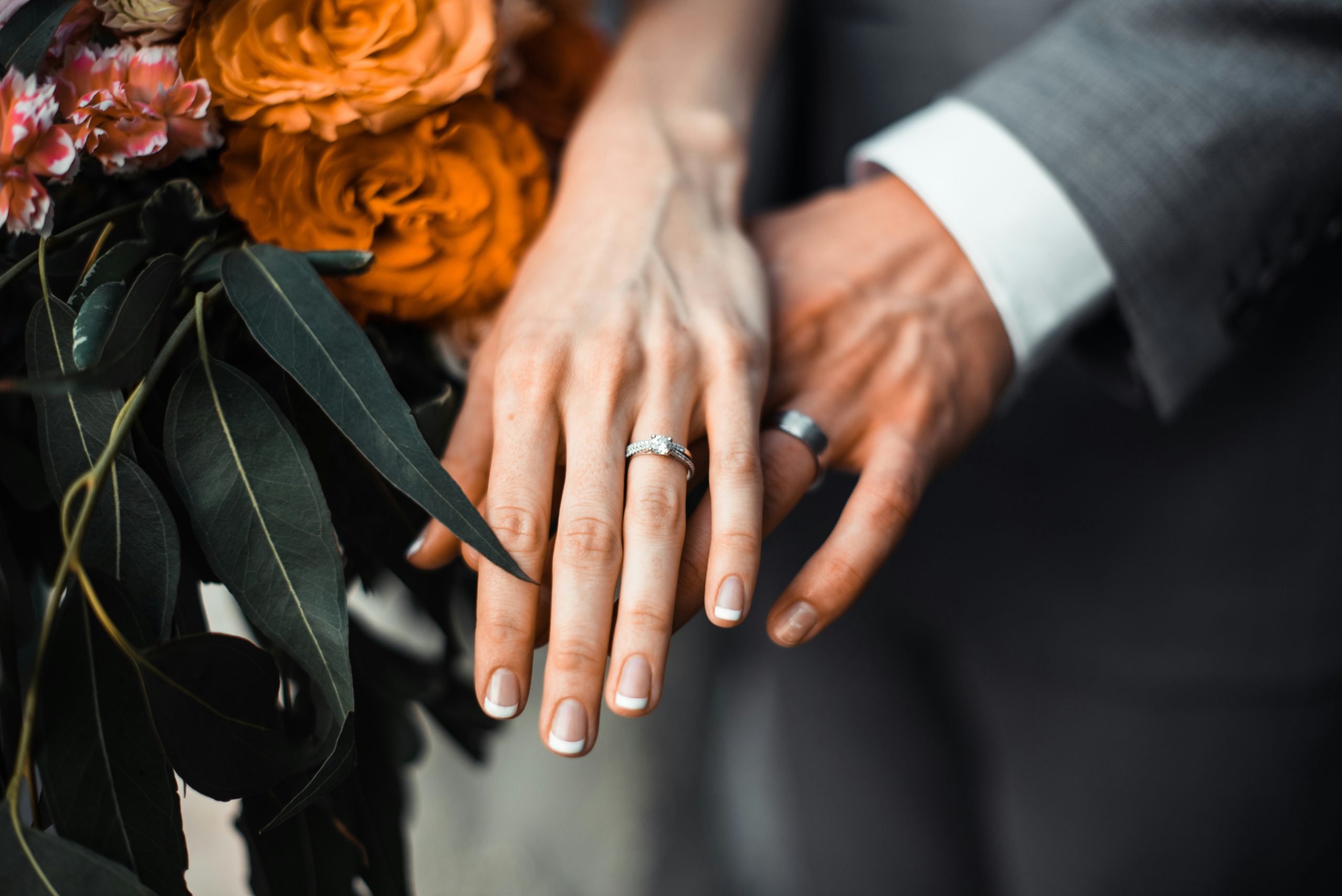A close-up of a bride and groom holding hands, with their wedding attire visible, capturing an intimate moment from their ceremony