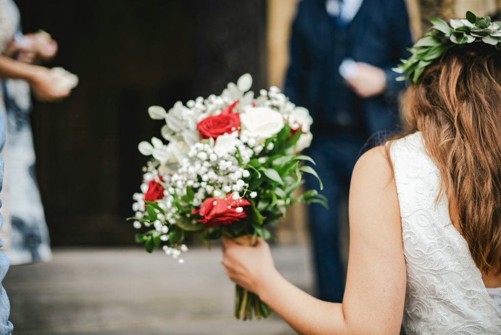 A bride holding her bouquet, poised and ready to enter her wedding ceremony, capturing a quiet moment before walking down the aisle