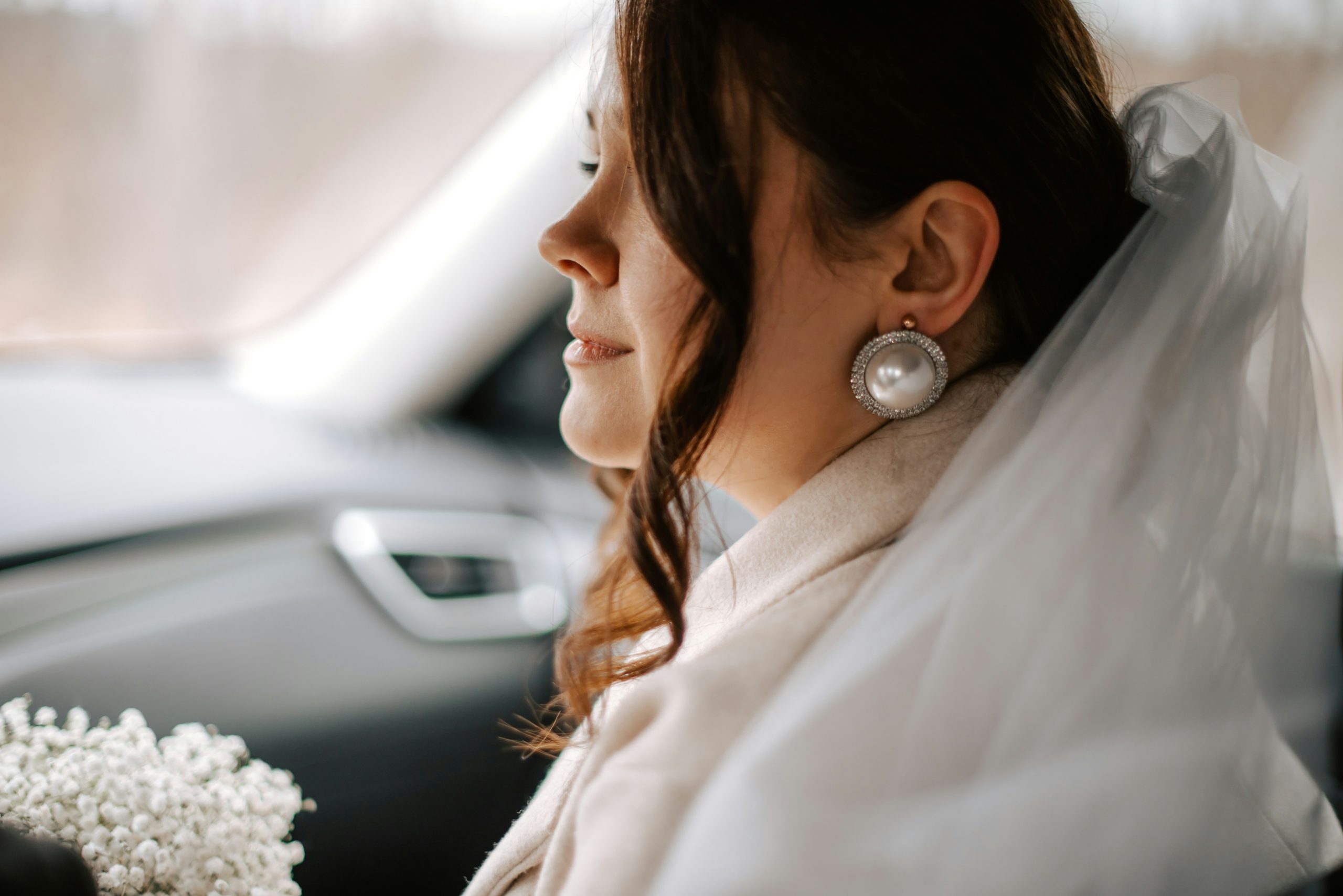 A bride sitting in a car on her way to the ceremony, smiling with a mix of excitement and nervous anticipation
