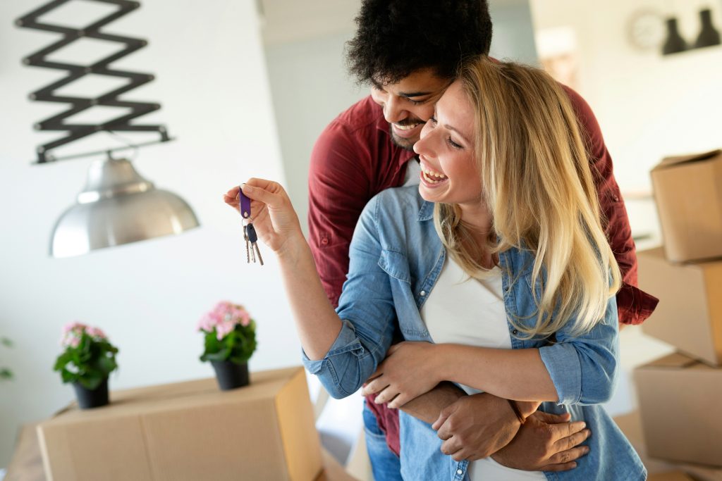 A couple hugging and laughing while holding house keys, celebrating the purchase of their new home
