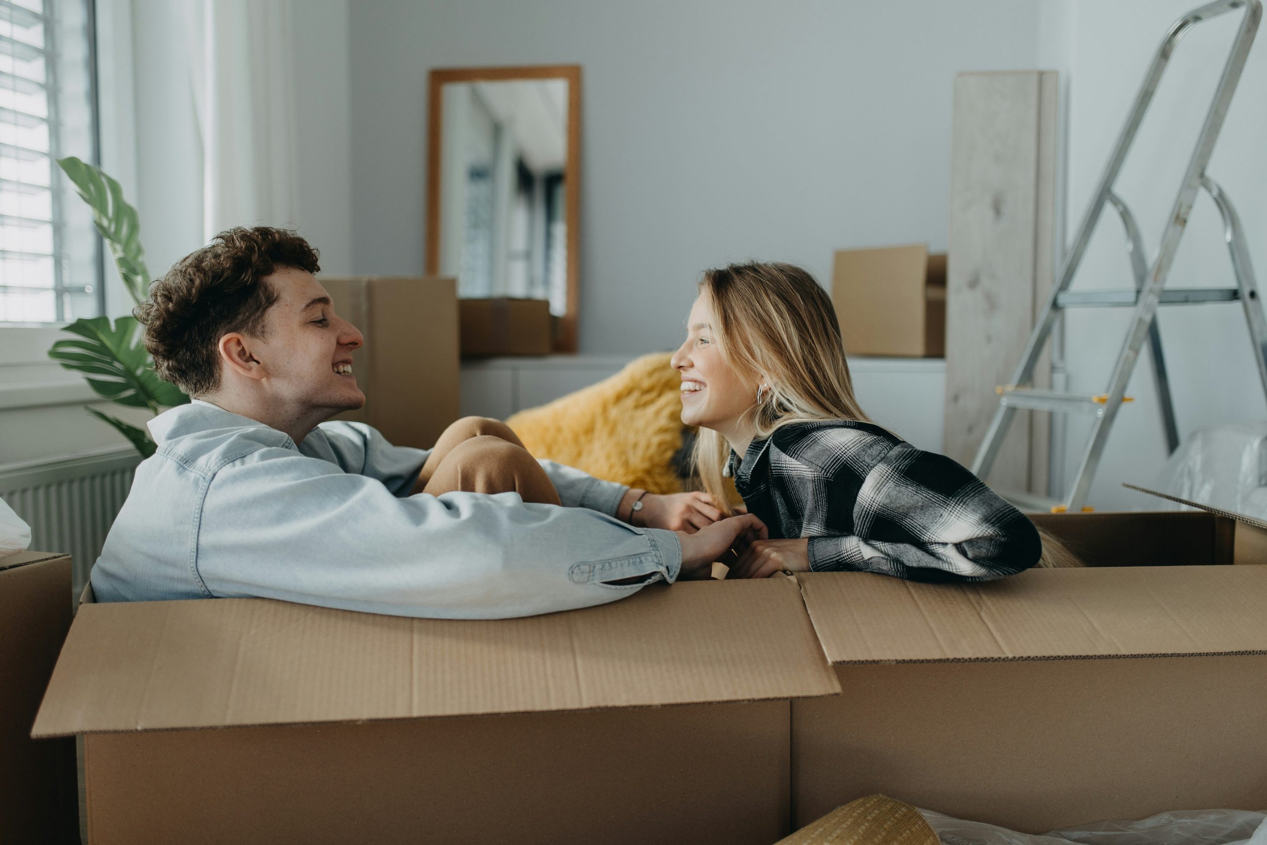 Couple celebrating their move into a new home A playful couple inside a cardboard box, laughing and celebrating as they move into their new home on moving day
