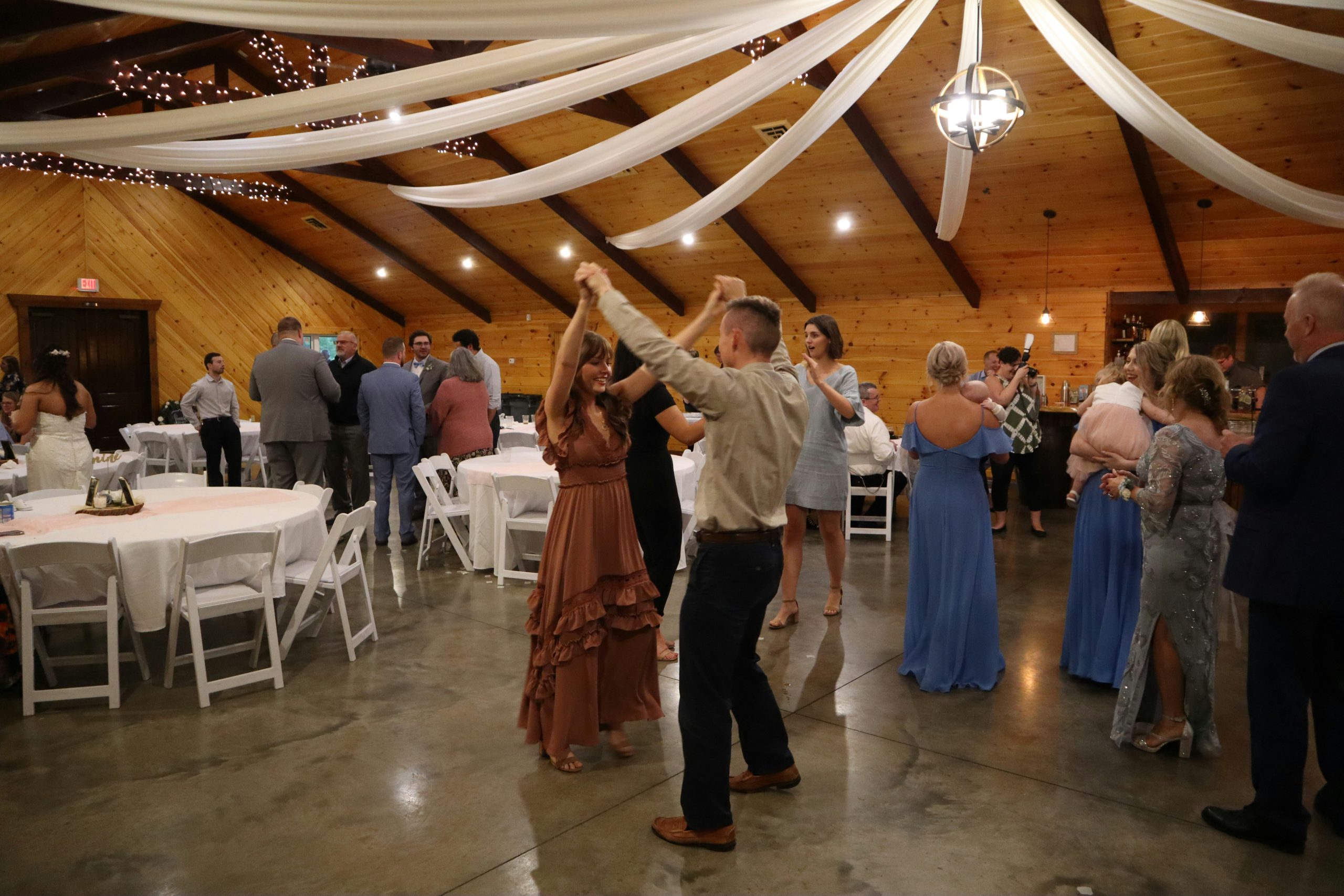 A couple dancing together at a wedding celebration in Ohio, set inside a large barn-style venue with a lively atmosphere
