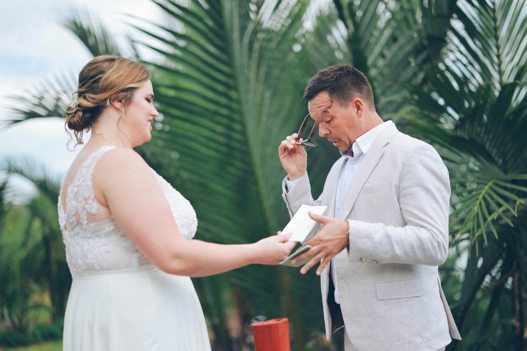 A groom at the altar putting on his glasses to read a letter or vows while holding a paper during the wedding ceremony
