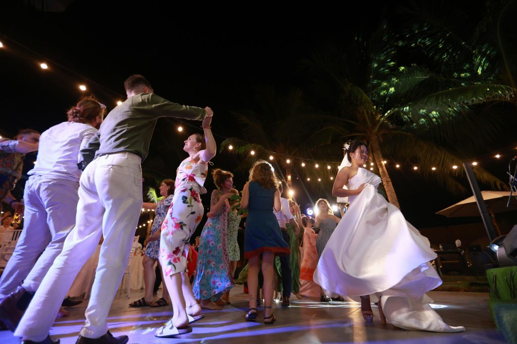 Guests dancing and celebrating at a nighttime wedding reception, enjoying the party atmosphere and music