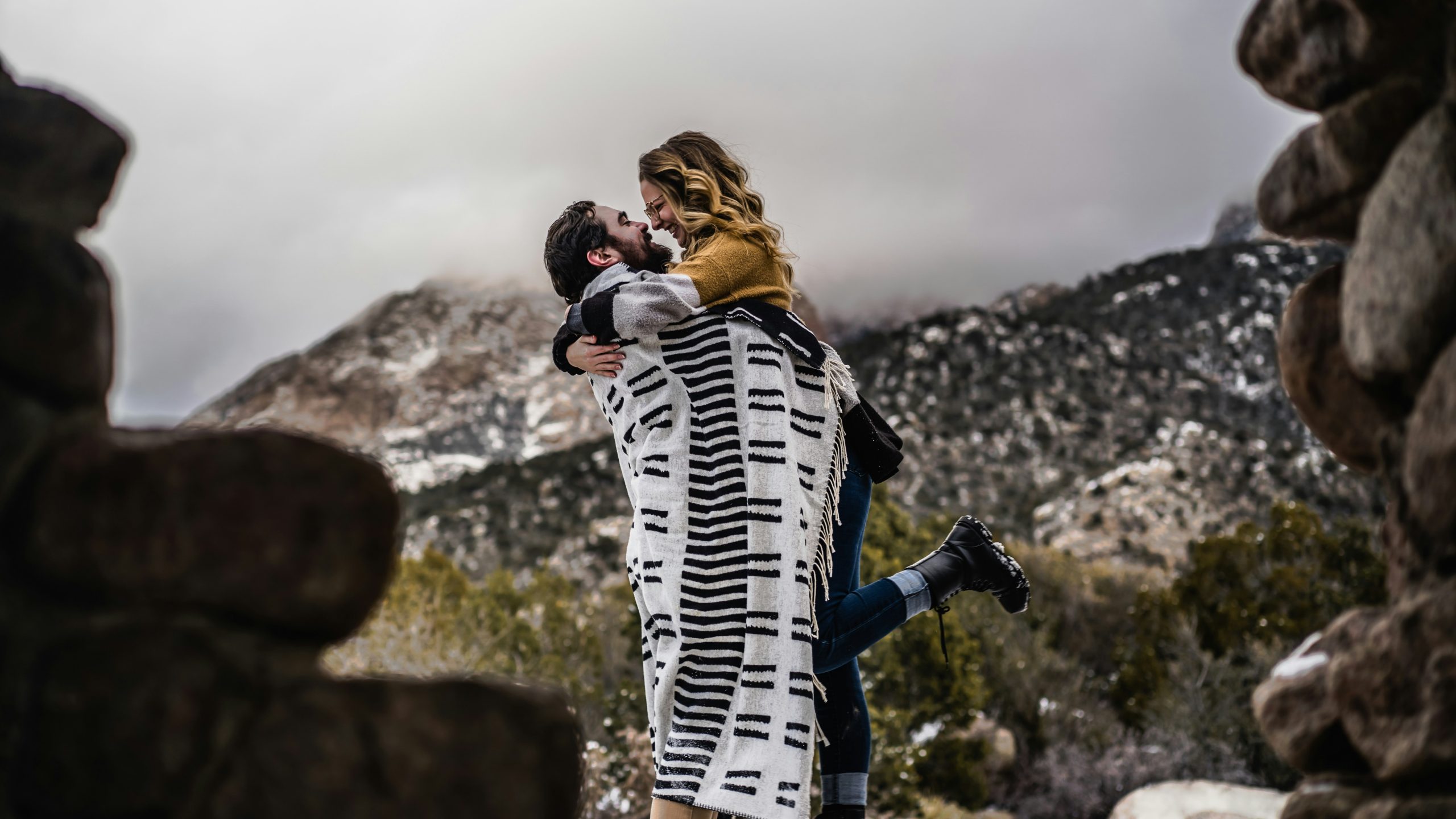 A bride and groom walking together outdoors on their wedding day in a warm, desert-like landscape, sharing a peaceful moment