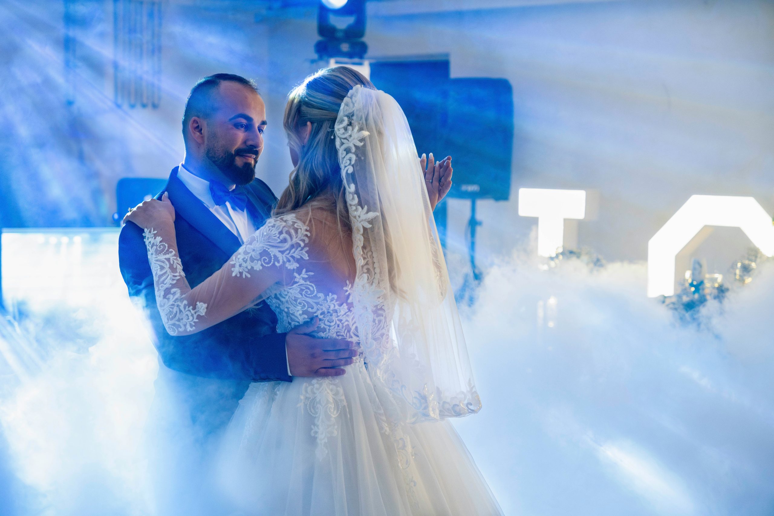 Couple dancing during wedding celebration A bride and groom dancing together under party lights while guests celebrate around them at the reception