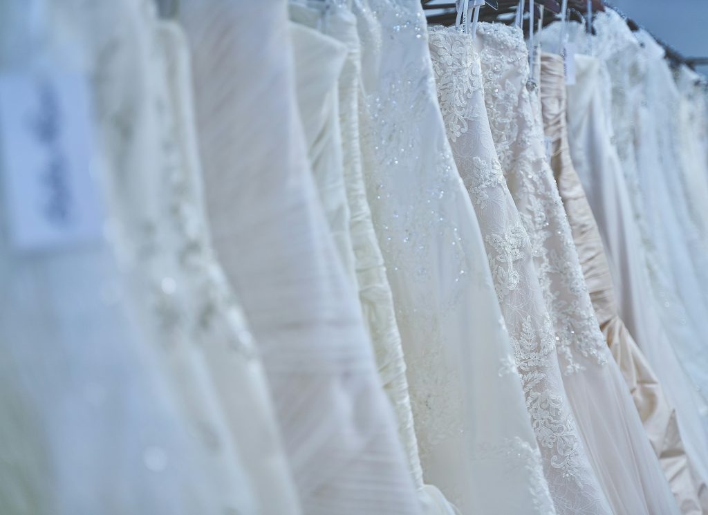 Several wedding dresses hanging on a rack, showcasing different styles and designs lined up together