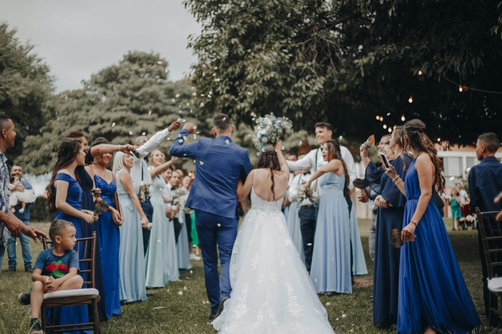 A couple walking hand in hand while guests line both sides, forming a celebratory aisle during the wedding ceremony