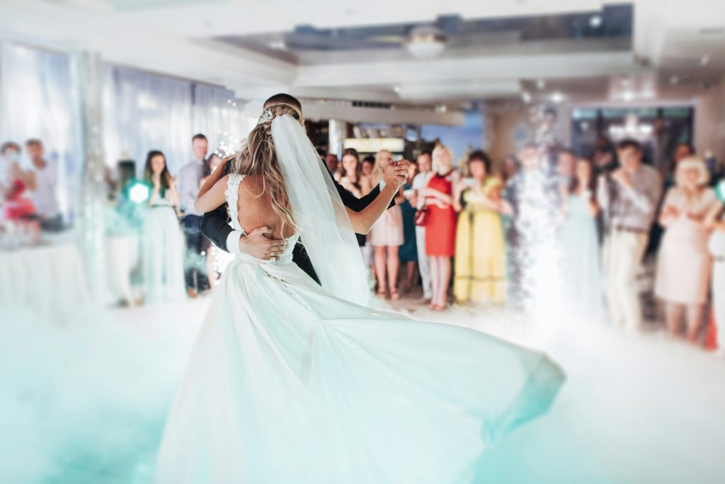 A lively wedding reception showing the couple dancing surrounded by colorful lights, music, and a festive celebration atmosphere