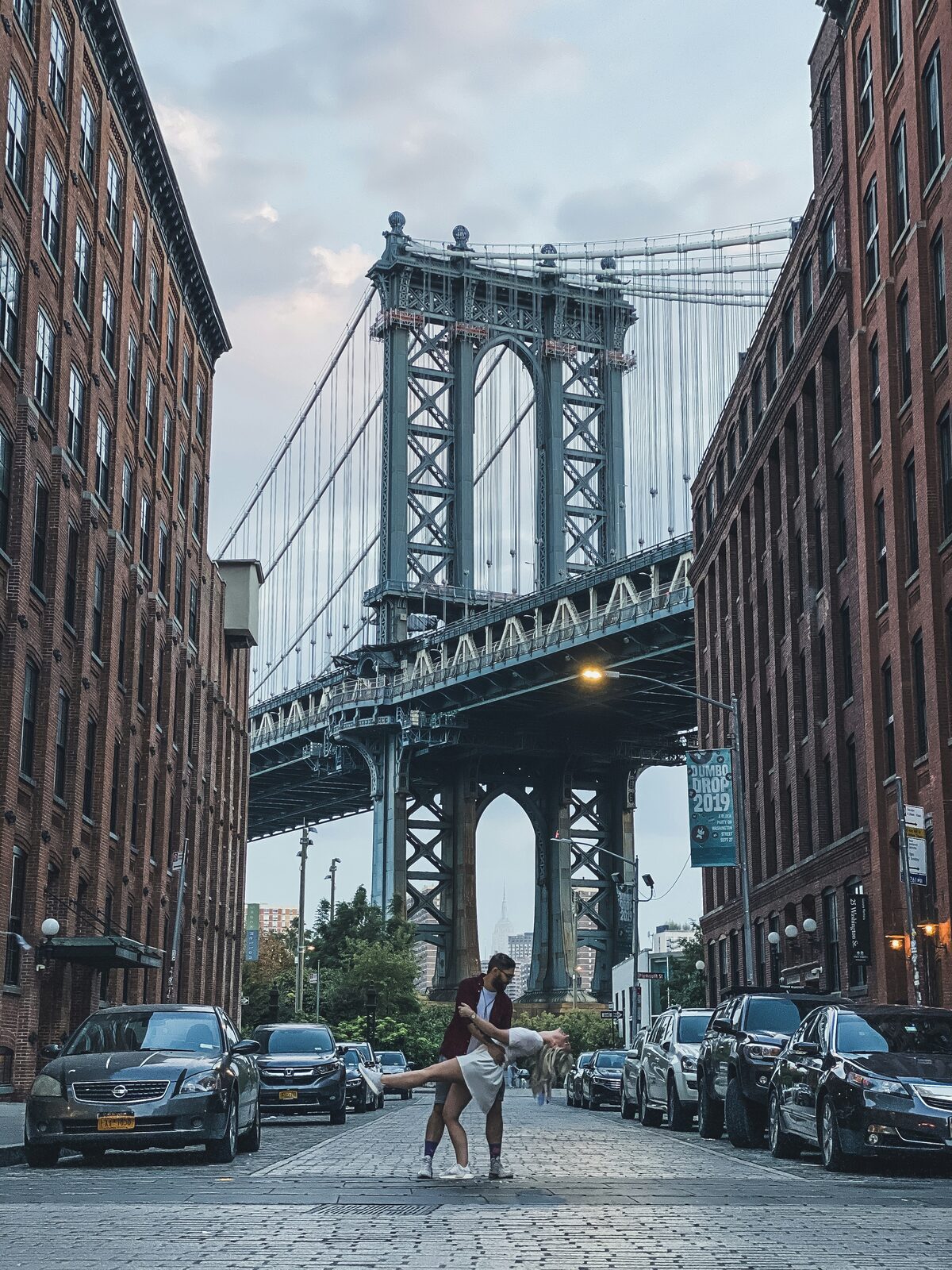 New York couple sharing a dance dip in Dumbo under the Manhattan Bridge, celebrating their engagement