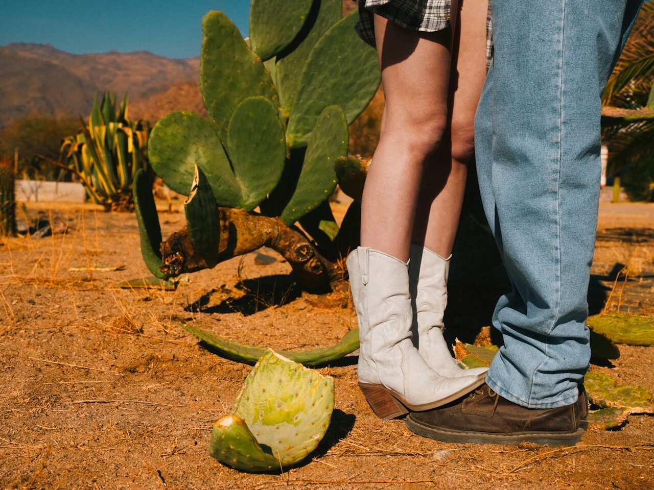 Polaroid photo of an engaged couple in cowboy boots posing in the desert next to a cactus, southwest engagement style
