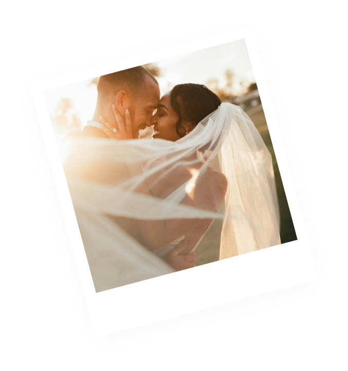 Polaroid photo of a couple kissing under the bride's veil at sunset