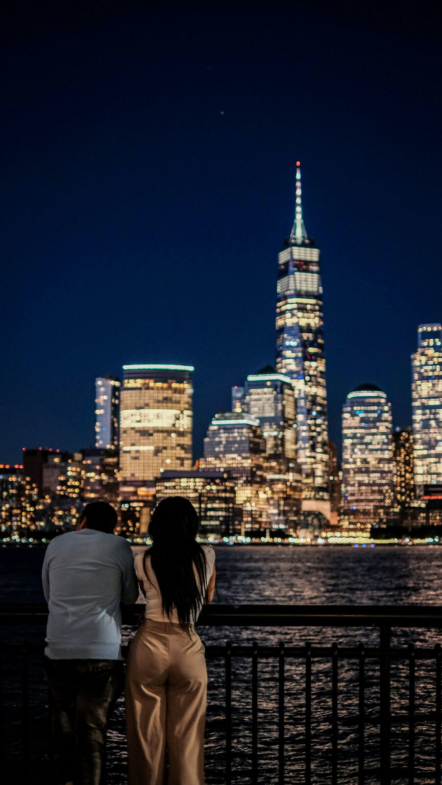 New York couple overlooking the Lower Manhattan skyline and Freedom Tower at night