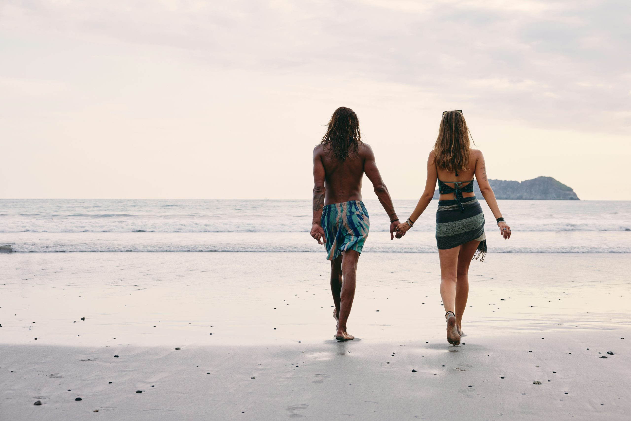 Couple walking together on the beach at sunset