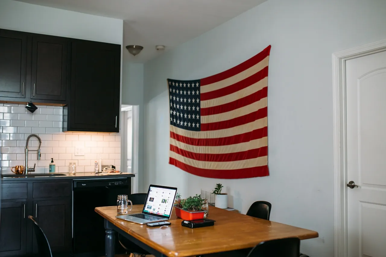 Person creating a HelloPrenup prenup on a laptop at a kitchen table with a small American flag, representing US state availability