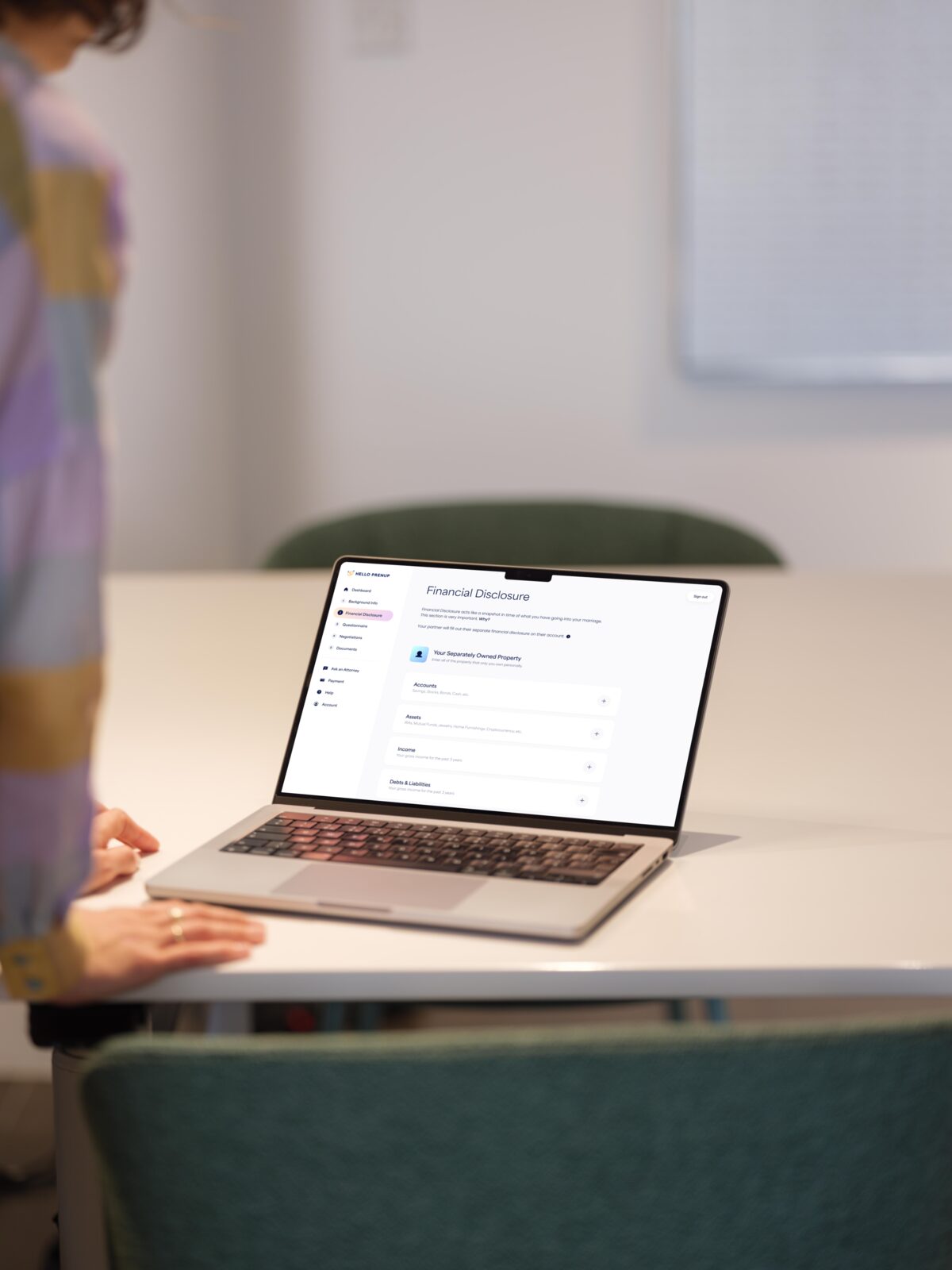 Person completing the HelloPrenup financial disclosure questionnaire on a MacBook Pro at an office desk