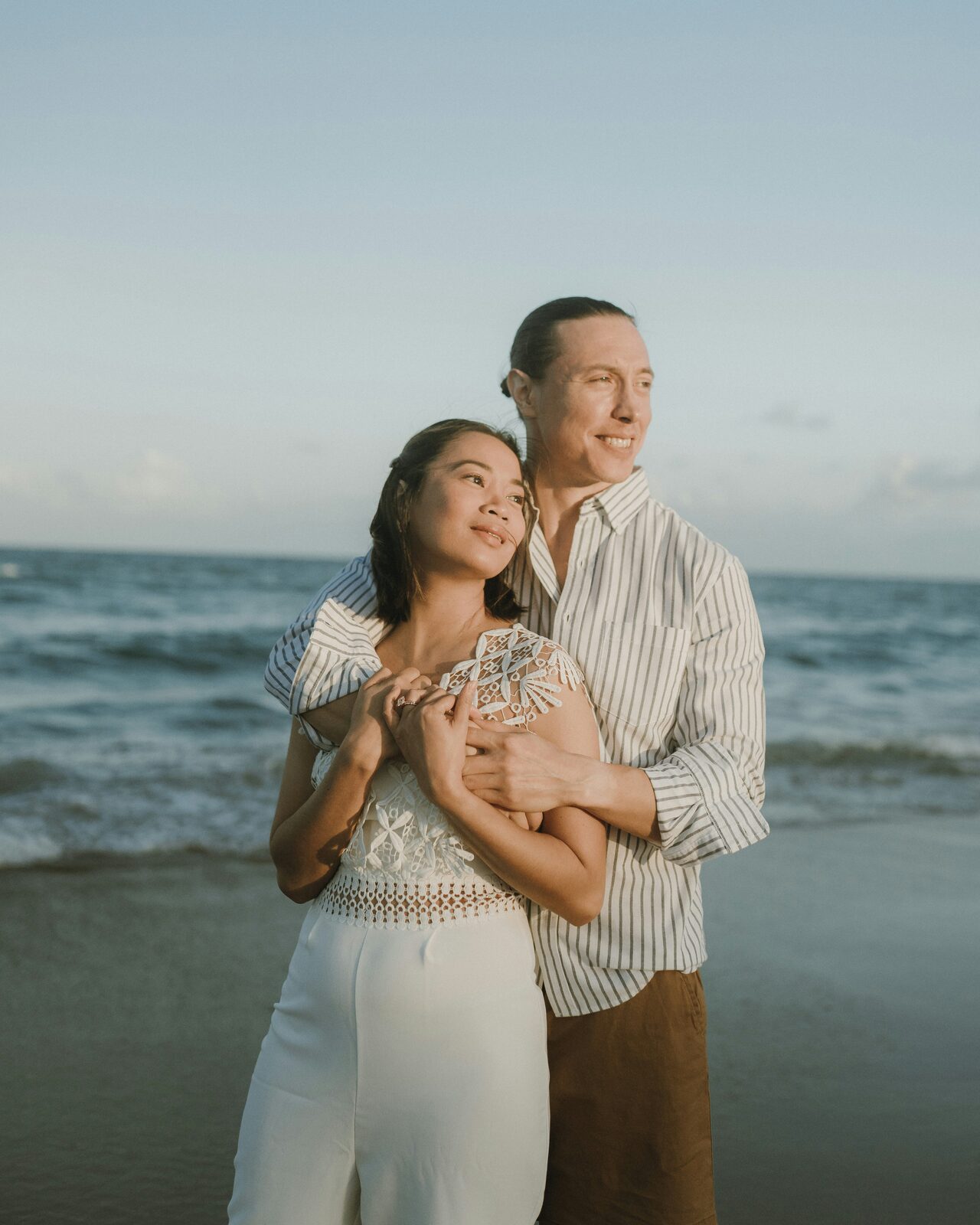 Engaged Florida couple embracing on the beach by the ocean after building their prenup