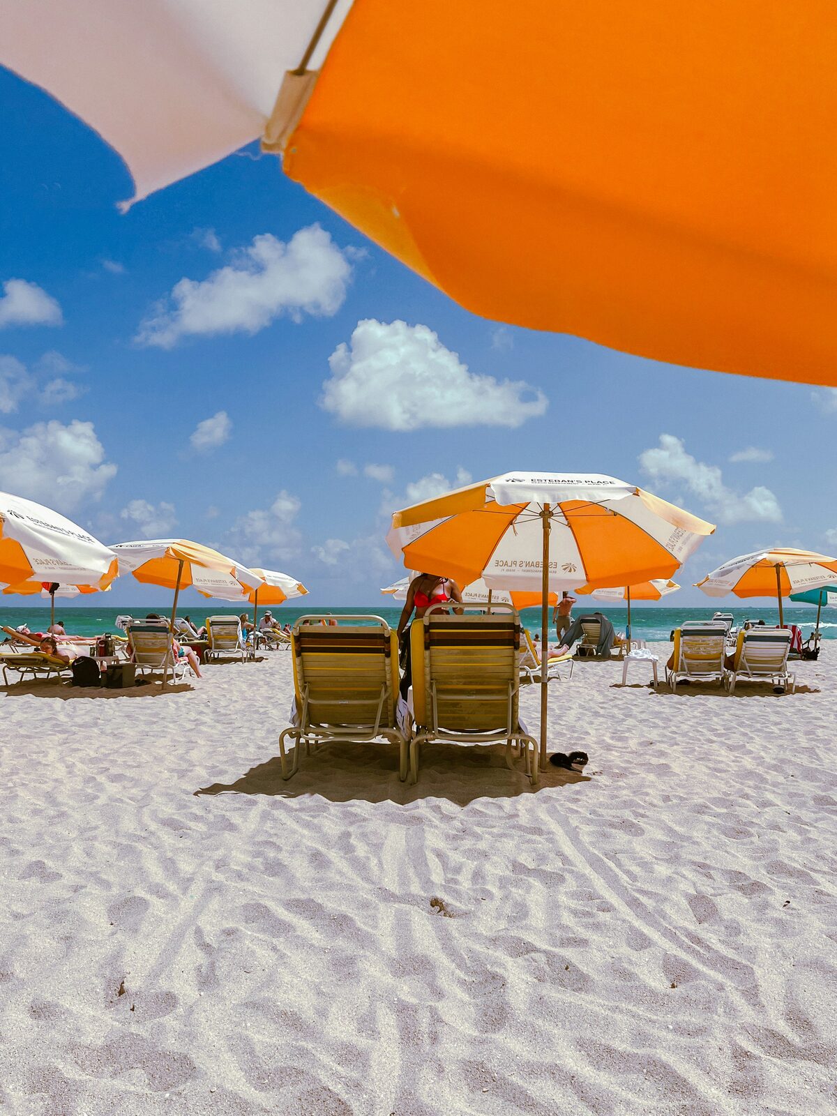 Two beach lounge chairs with orange umbrellas on a tropical Florida beach, the kind of vacation a HelloPrenup prenup helps protect