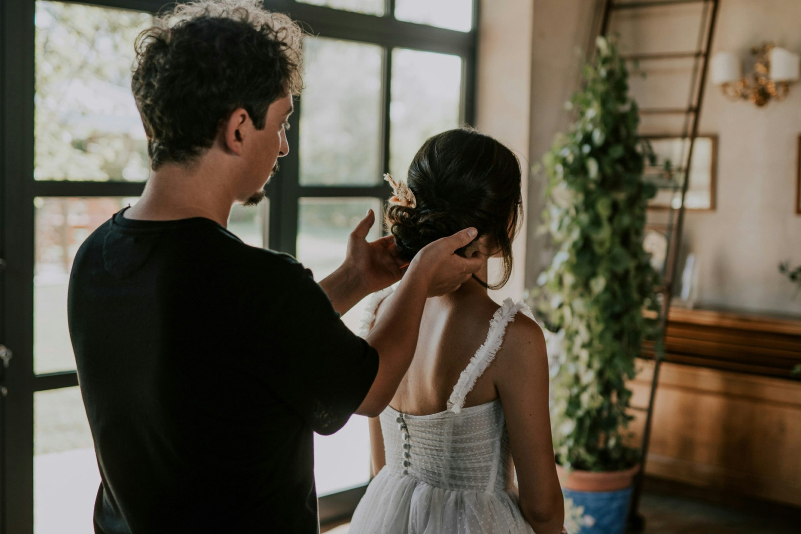 Bride having her hair styled before the wedding A bride sitting while a hairstylist arranges her hair during wedding preparations, capturing an important step in the wedding planning process.