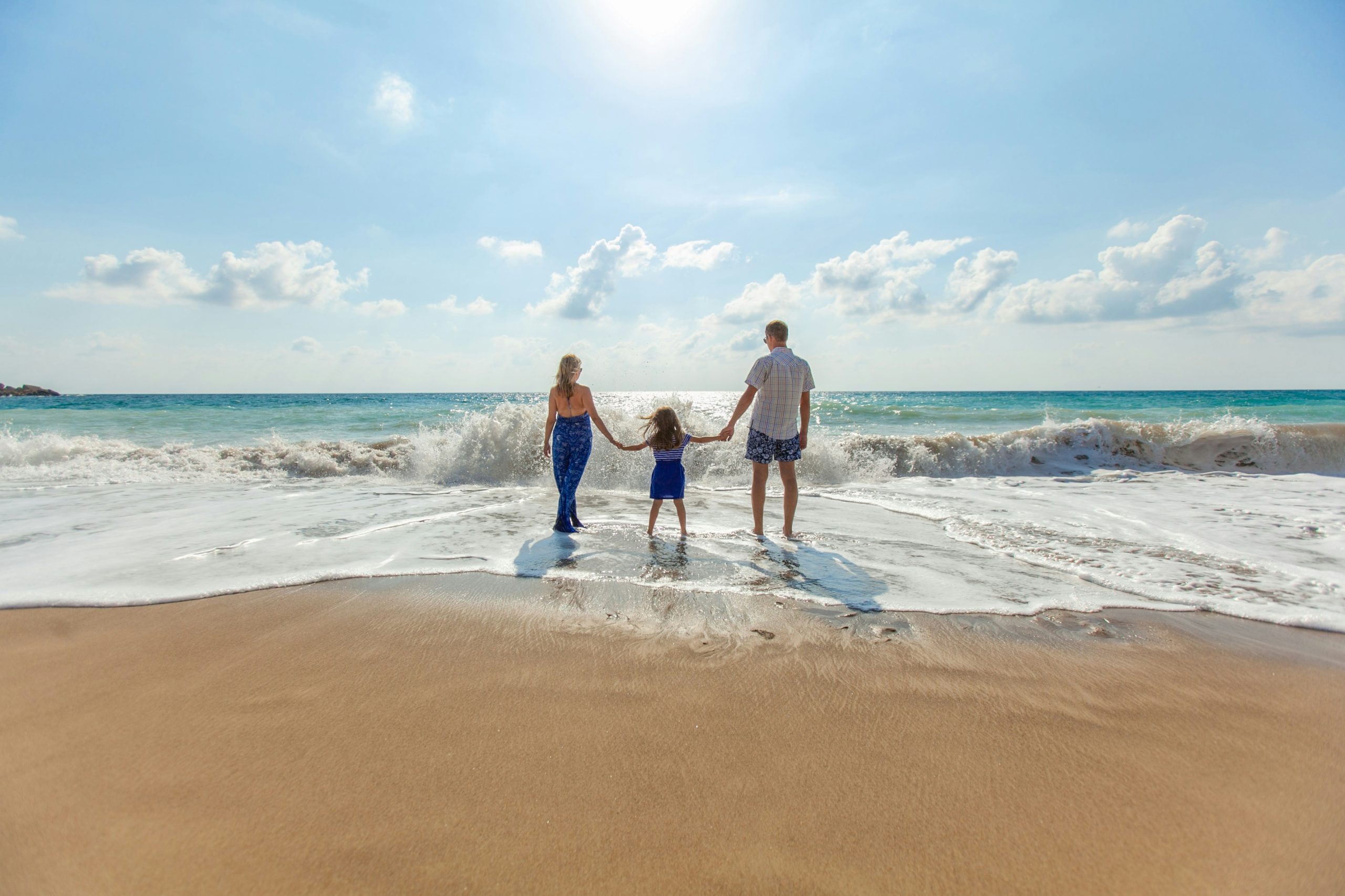 A happy family laughing and playing together by the ocean, enjoying a fun day at the beach under sunny skies