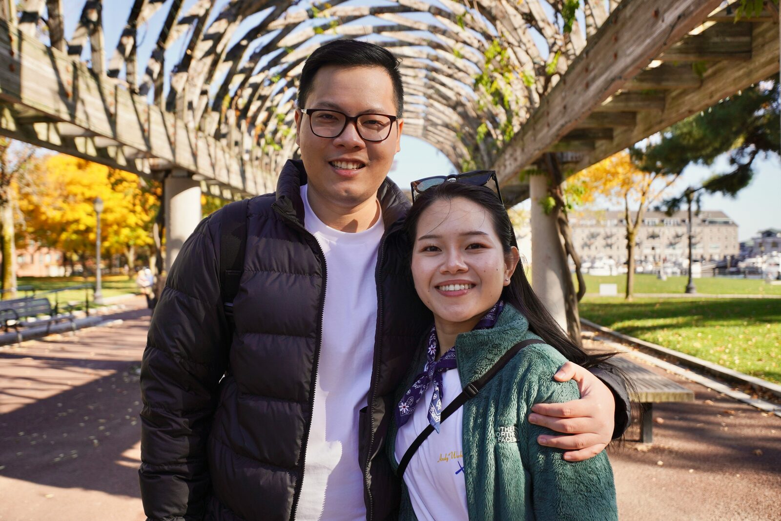 Engaged Massachusetts couple smiling at the Boston waterfront on a fall day, exploring their prenup options