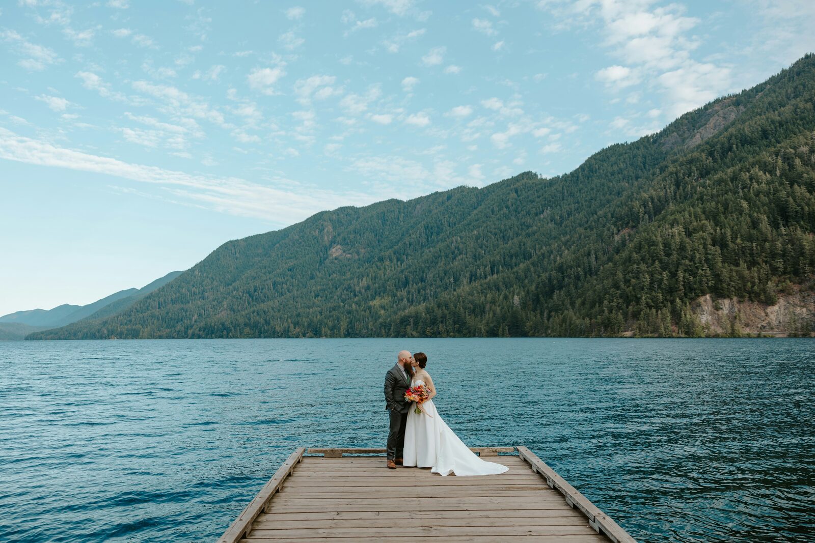 Washington bride and groom kissing on a dock at Lake Crescent in the Pacific Northwest mountains