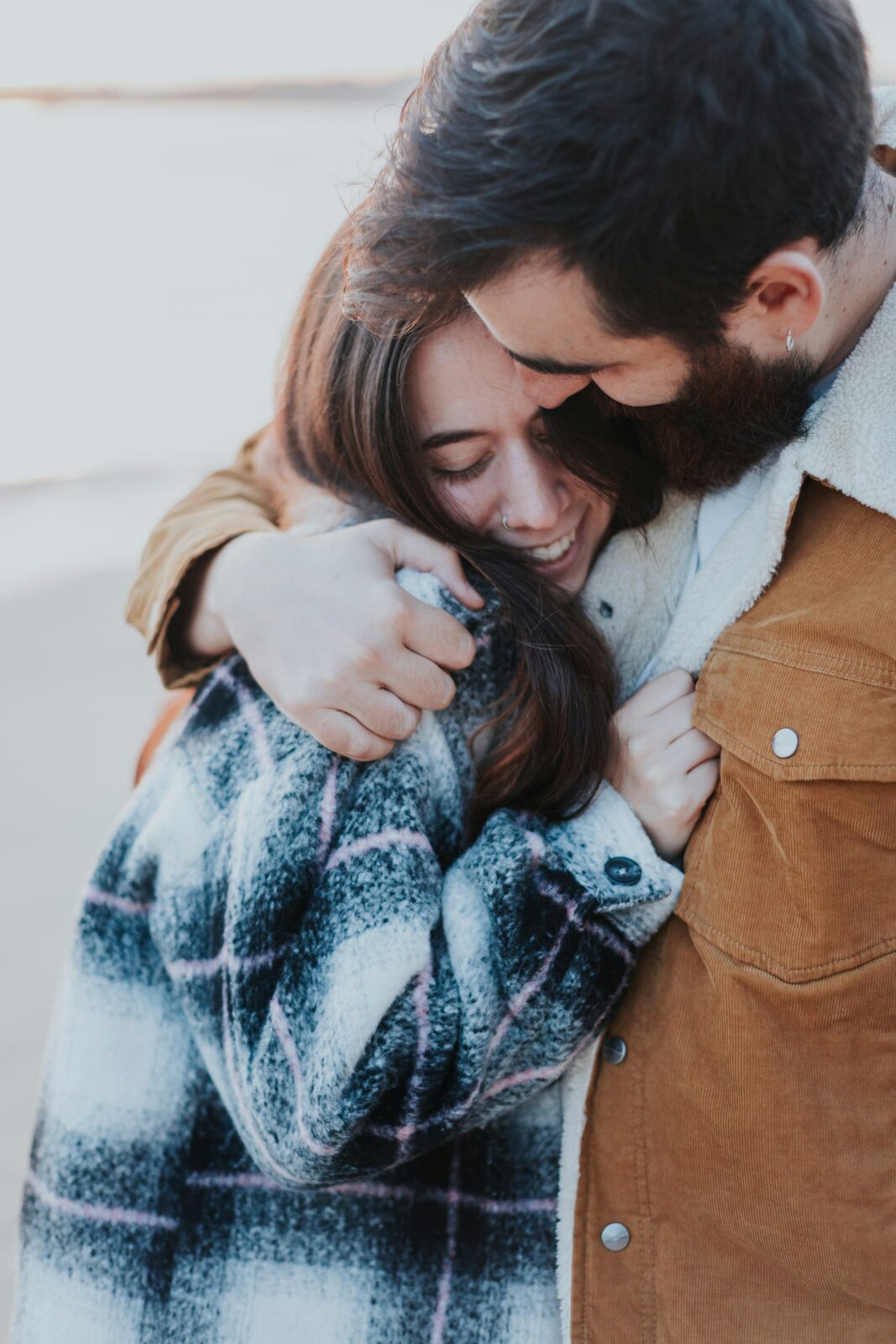 Married couple hugging and laughing together in cozy coats