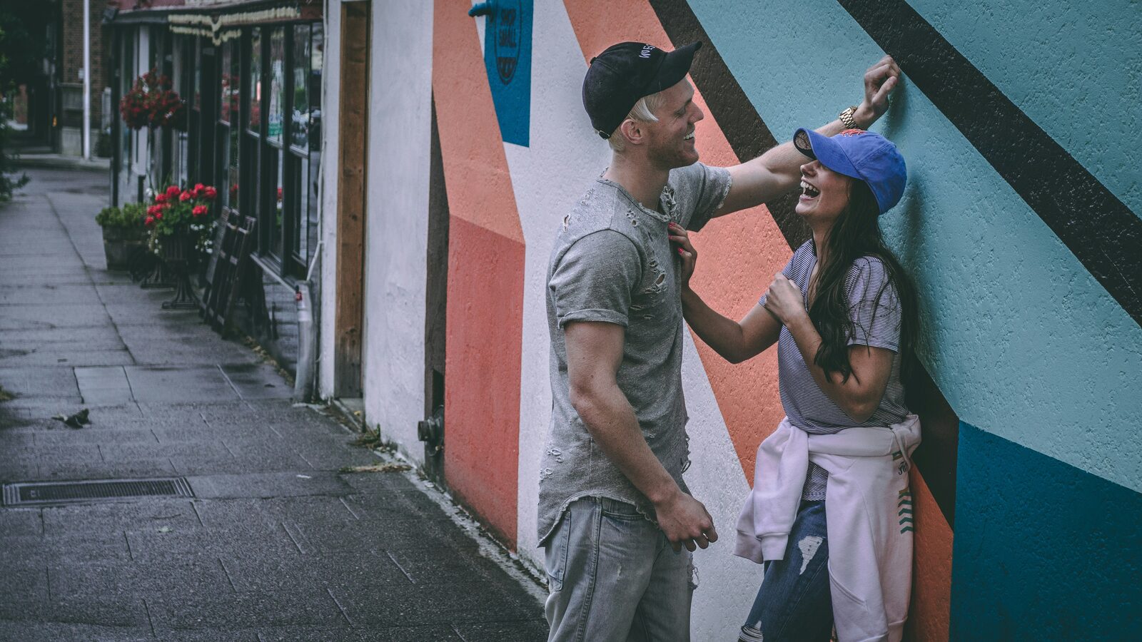 Washington couple laughing in front of a colorful street-art mural, celebrating their engagement
