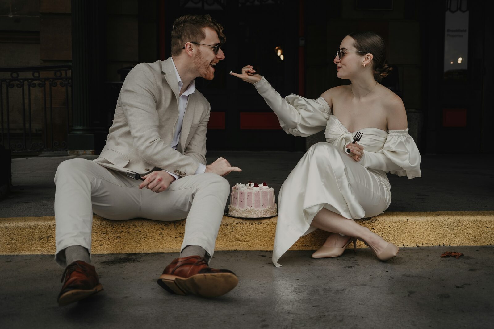 Newlywed Pennsylvania couple sharing wedding cake on a Pittsburgh sidewalk