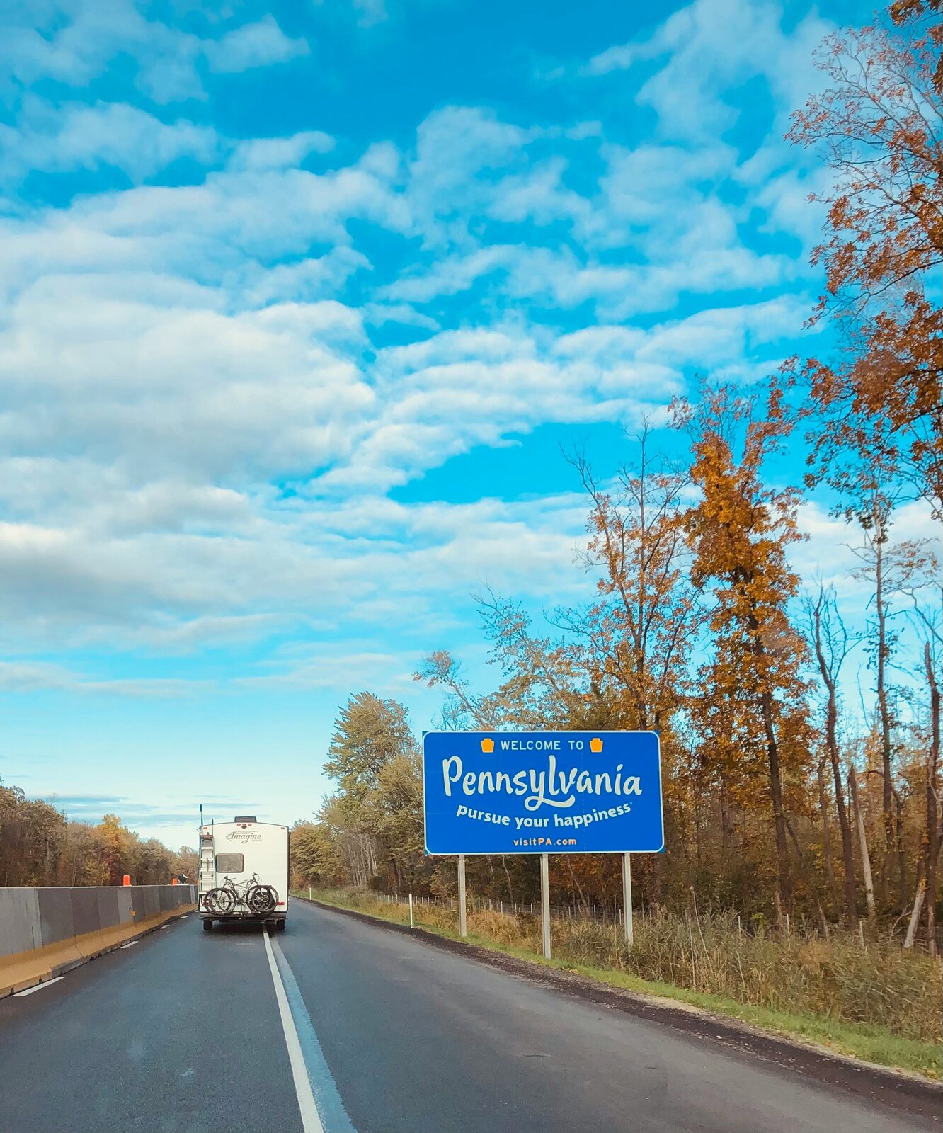 Welcome to Pennsylvania highway sign along a tree-lined autumn road