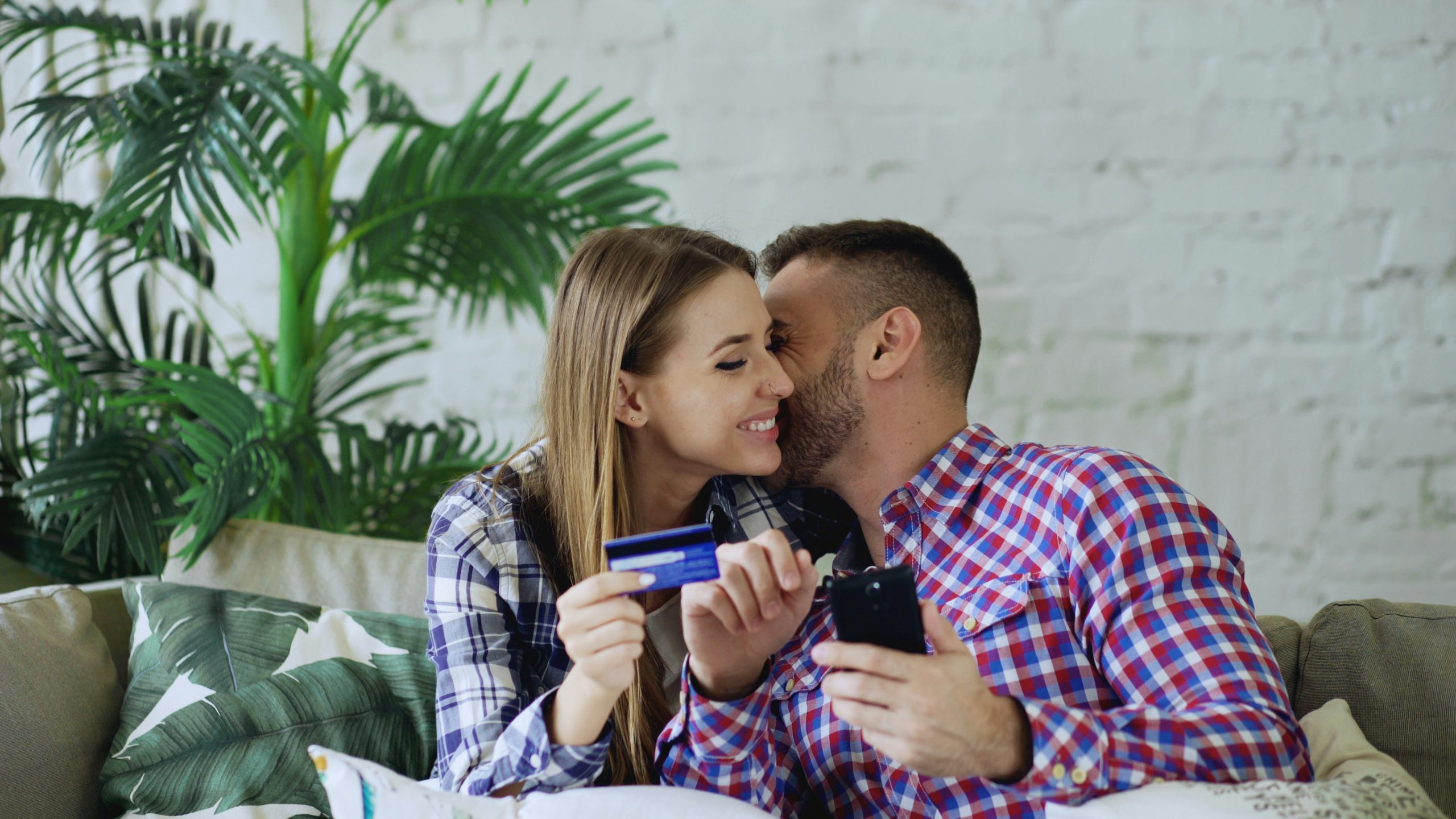 Couple shopping online together at home A smiling couple using a laptop to shop online while holding a credit card, enjoying the experience together at home.