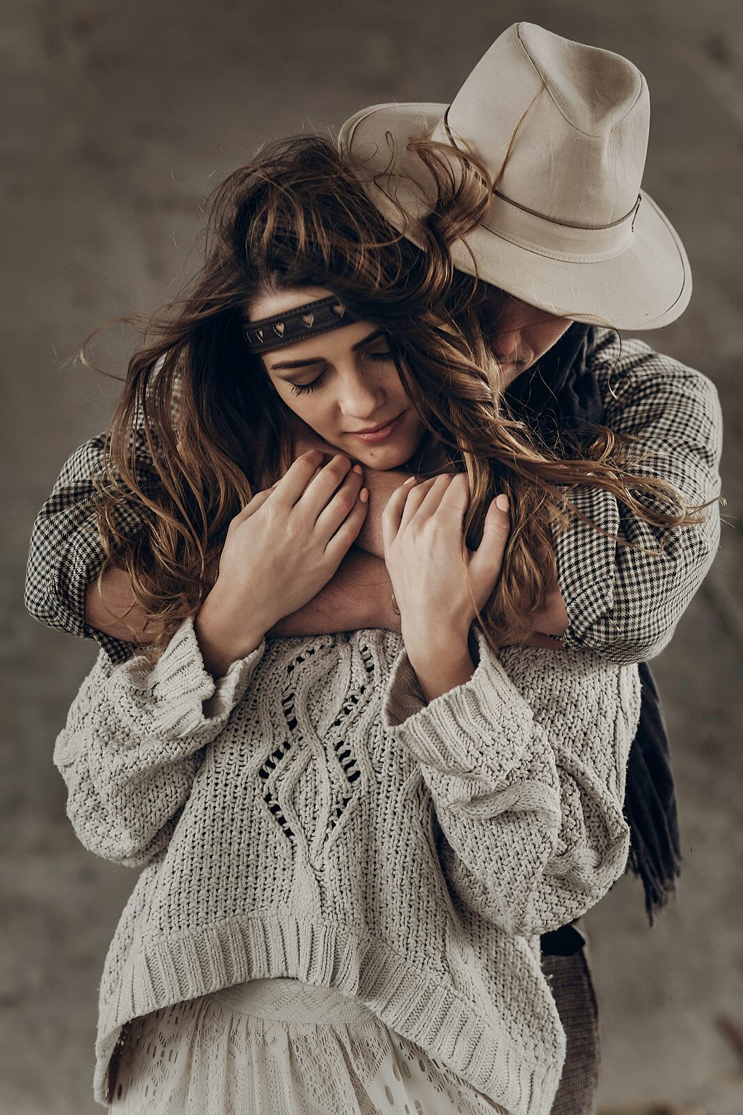 Oklahoma couple in a cowboy hat and cream sweater embracing as they prepare to build their prenup