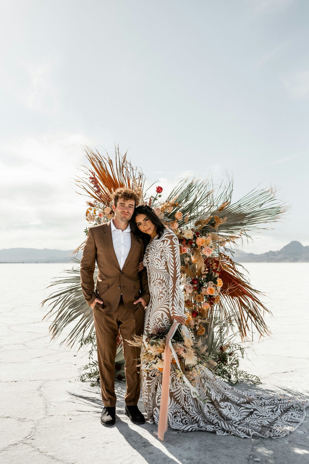 Bride and groom under a boho floral arch on the desert salt flats, protected with a HelloPrenup prenuptial agreement