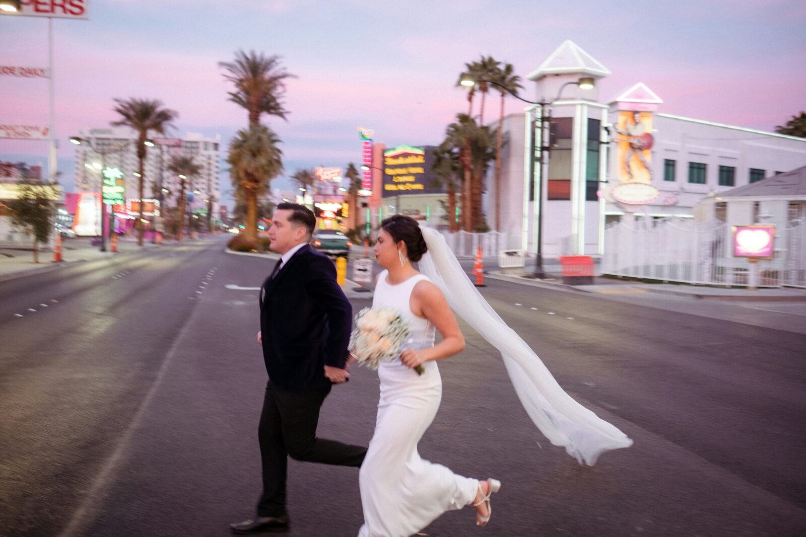 Bride and groom running across Fremont Street in Las Vegas at sunset after their Nevada elopement