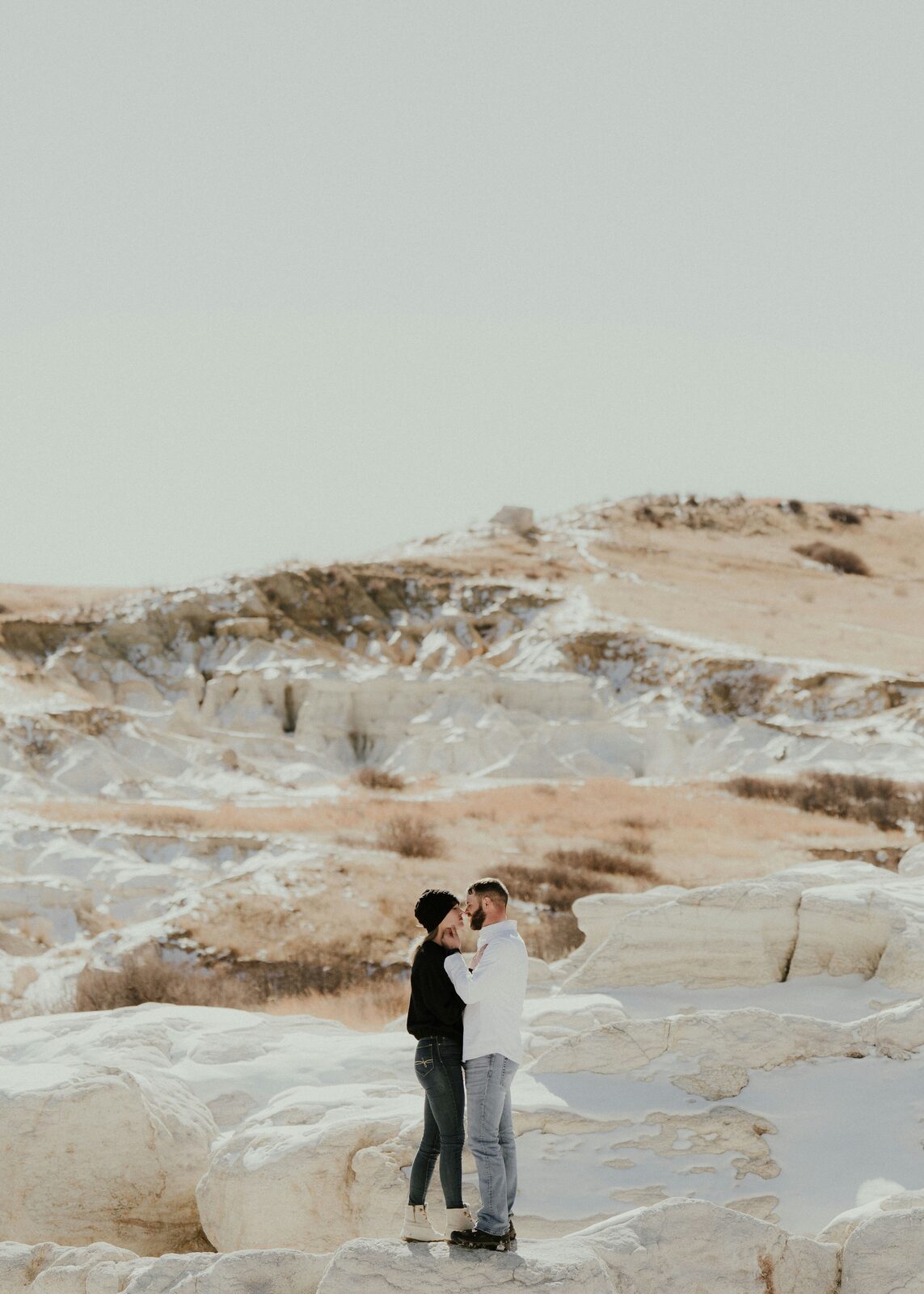 Colorado couple embracing at the Paint Mines during a snowy winter engagement