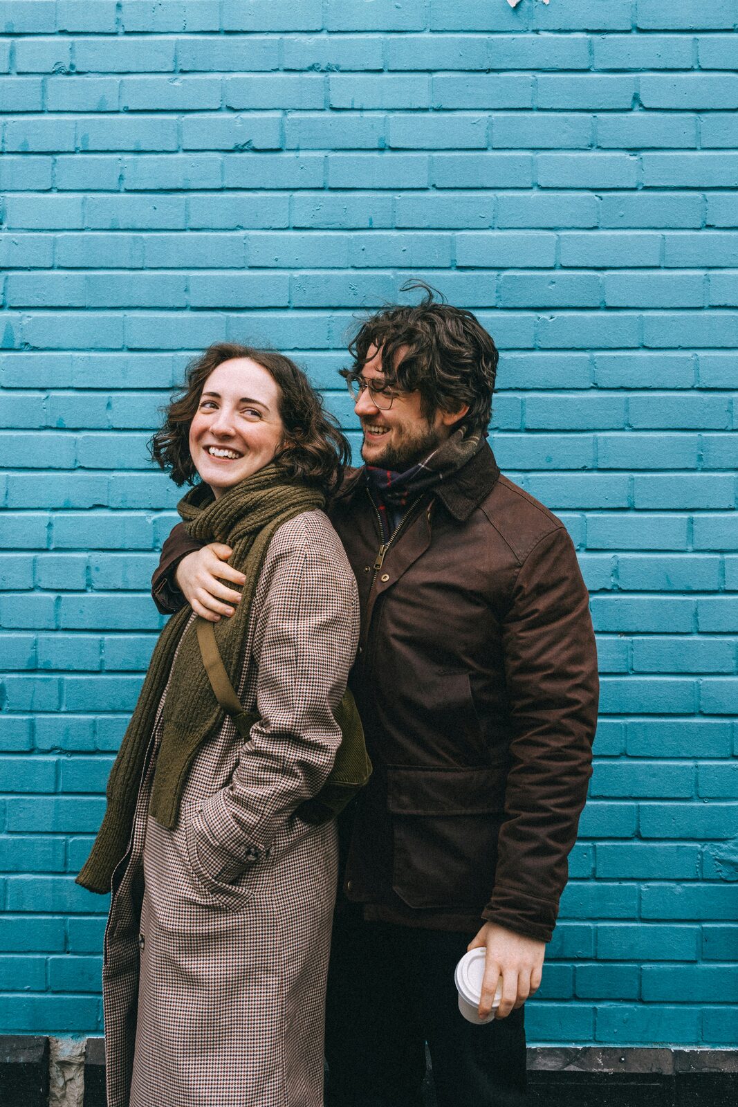 West Virginia couple hugging in front of a blue brick wall, learning about prenups