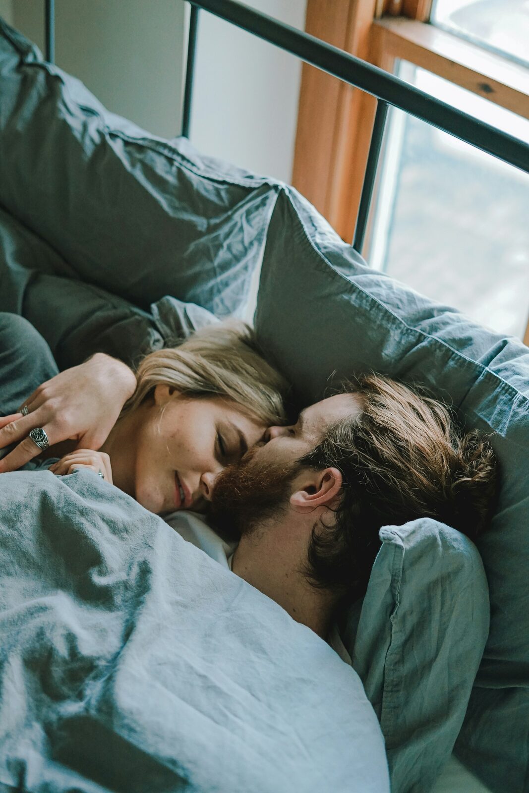 West Virginia couple cuddling in bed in the morning light, preparing to build their prenup