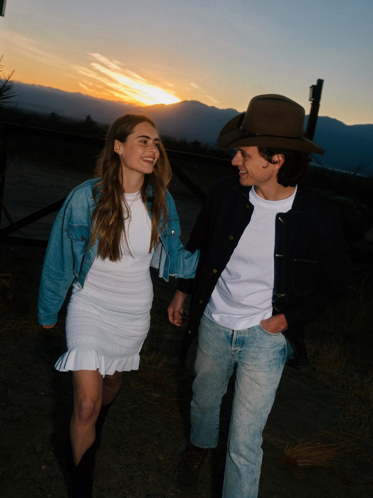 Oklahoma couple walking arm in arm at sunset in western wear