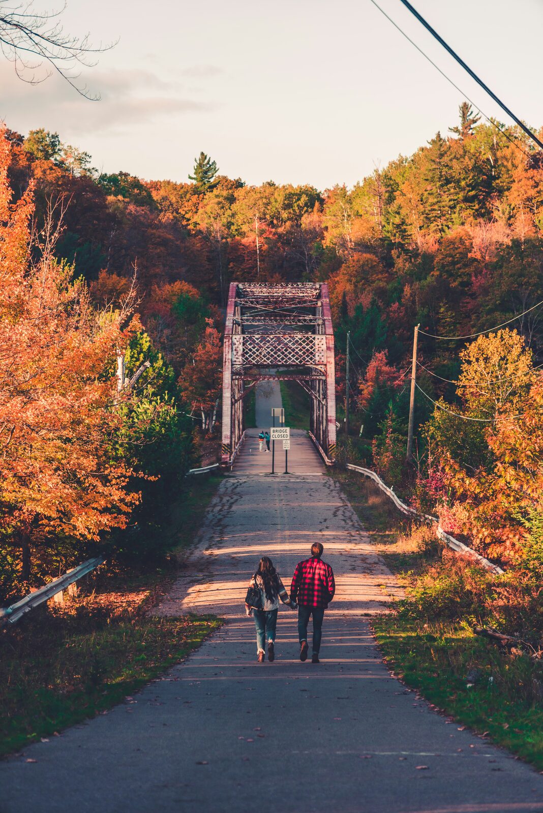 Michigan couple walking toward a truss bridge in autumn, talking through how marital property is divided