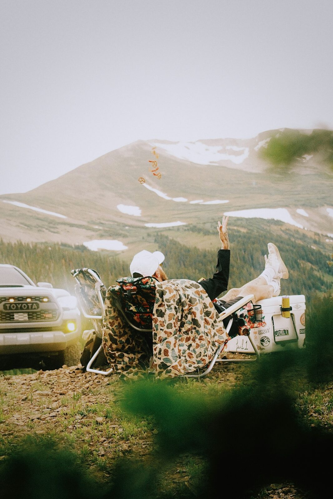 Colorado adventurer relaxing in a camp chair beside a Toyota Tacoma with a mountain view